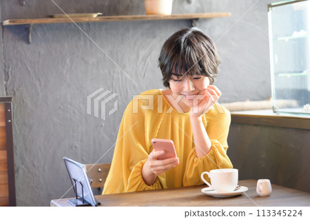 A woman operating a smartphone at a cafe "Western confectionery store sentiment" 113345224