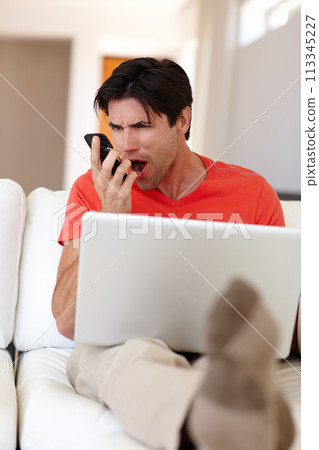 Man, angry and phone call in living room with laptop for business, entertainment or work from home. Person, notebook and mobile upset for communication, deal or conversation with network provider 113345227