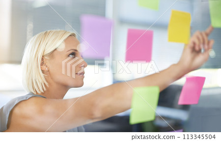 Woman, glass and board with pointing, thinking and notes for planning, proposal and idea development. Person, wall and paper for brainstorming process, decision or choice with smile in modern office 113345504