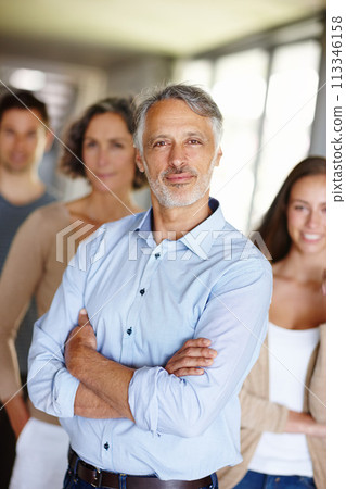 Teamwork, portrait and senior businessman in office, leader or CEO in workplace with team. Face, smile and manager with management at design business firm, collaboration and professional company 113346158