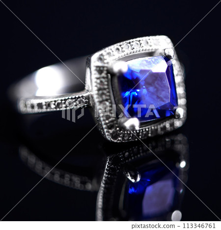 Sapphire, silver ring and studio by black background for closeup, vintage product and luxury. Tanzanite, blue gemstone and white gold with precious metal for jewelry, shine and glow with reflection 113346761