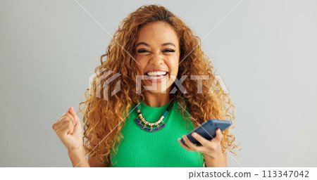 Excited woman, winner and phone with good news for lottery, prize or promotion on a gray studio background. Happy female person dancing with smile and mobile smartphone for celebration or success Excited woman, winner and phone with good news for lottery, prize or promotion on a gray studio background. Happy female person dancing with smile and mobile smartphone for celebration or success 113347042