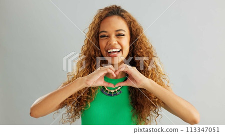Happy woman, love and care with heart hands for romance or trust on a gray studio background. Portrait of female person or model with smile, like emoji or shape for romantic gesture on mockup space 113347051