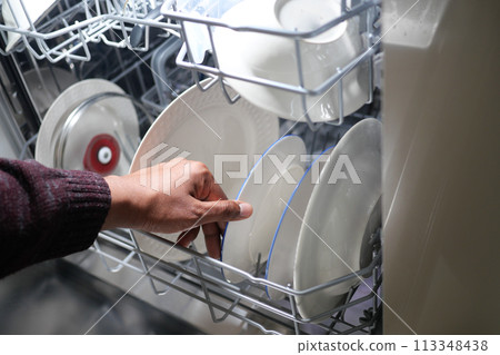 A young man opens takes out clean white utensils.  113348438