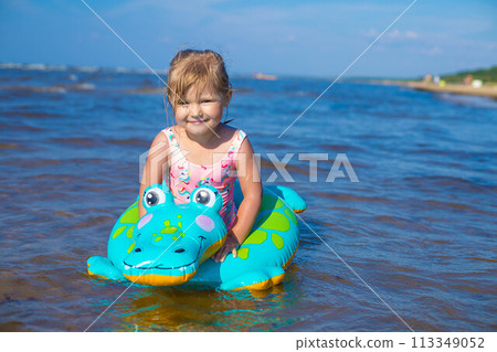 Happy girl swimming on an inflatable crocodile toy in the sea 113349052