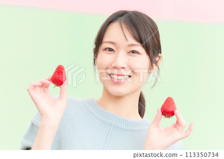 Smiling young woman holding strawberries in her hands 113350734