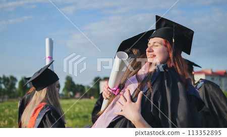 Two college graduates girls hugging on a sunny day. Two college graduates girls hugging on a sunny day. 113352895