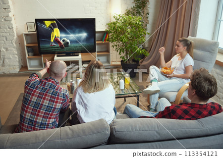 Friends, sport fans meeting at home, sitting on couch in living room on daytime and watching online football match translation. Friends, sport fans meeting at home, sitting on couch in living room on daytime and watching online football match translation. 113354121
