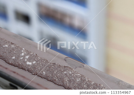 frost on the metal cornice near the window against the background of the facade of a building. frost on the metal cornice near the window against the background of the facade of a building. 113354967