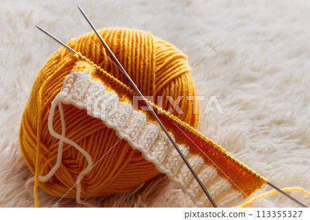 Yellow knitting yarn and knitting needles. Knitwear fashion. Wool socks and needles. Knitting hobby. Handcraft clothing. Needlework concept. Wool knitted socks. Homemade crochet footwear. 113355327