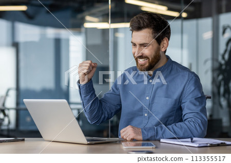 Young professional exults with a fist pump at his desk in a modern office setting, symbolizing success and achievement. Young professional exults with a fist pump at his desk in a modern office setting, symbolizing success and achievement. 113355517