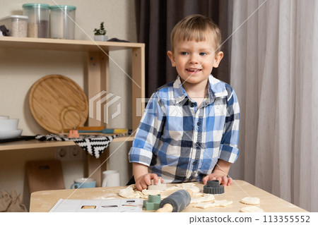 A two-year-old boy cooking in the kitchen, making dough. Cooking and kids 113355552