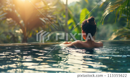 Beautiful woman on vacation relaxing in swimming pool at luxury tropical resort. Back view Beautiful woman on vacation relaxing in swimming pool at luxury tropical resort. Back view 113355622