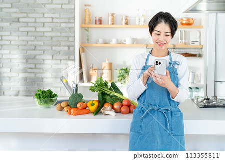 A smiling young woman standing in the kitchen 113355811
