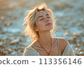 Sensual beautiful young woman enjoys sunrise on beach, with warm tones 113356146