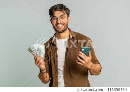 Happy Indian man use smartphone rejoicing game win receiving money dollar cash celebrating success 113356554