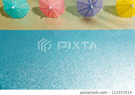 Abstract beach with glitter paper sand and water and cocktail umbrellas. Summer aesthetic mockup template background on a tropical beach holiday 113357614