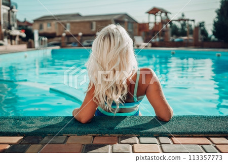 Happy woman in bikini sitting near swimming pool, summer vacation. Happy woman in bikini sitting near swimming pool, summer vacation. 113357773