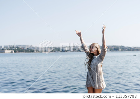 A woman is standing on a dock by the water, wearing a dress and a pair of black shoes. She is smiling and she is happy. A woman is standing on a dock by the water, wearing a dress and a pair of black shoes. She is smiling and she is happy. 113357798
