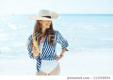 smiling elegant woman on beach with spf 113358054