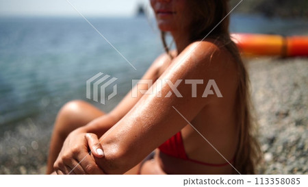 Woman beach sea. Women's legs by the sea and women's hands are smeared with sunscreen. Slow motion video of a beautiful woman smearing sunscreen. Summer travel holidays vacation on the sea. 113358085