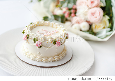 Festive bento cake and bouquet on a light background Festive bento cake and bouquet on a light background 113358179