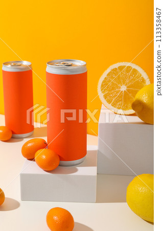 Tin cans and citrus fruits on white blocks on orange background Tin cans and citrus fruits on white blocks on orange background 113358467