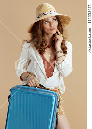 pensive trendy woman in blouse and shorts isolated on beige 113358475