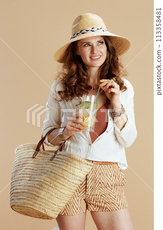 smiling stylish woman in blouse and shorts isolated on beige smiling stylish woman in blouse and shorts isolated on beige 113358481