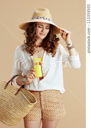 smiling trendy female in blouse and shorts isolated on beige 113358505
