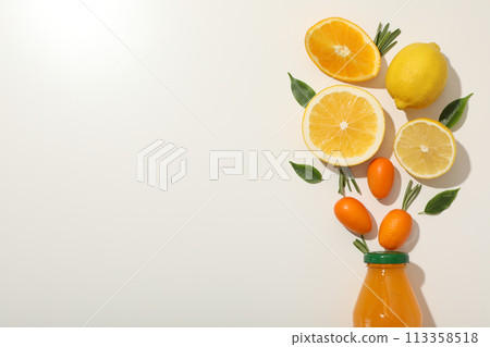 Glass bottle with juice and citrus fruits on white background, space for text 113358518