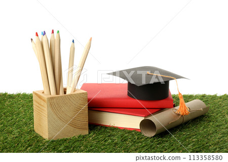 PNG, graduate hat with books on grass, isolated on white background. PNG, graduate hat with books on grass, isolated on white background. 113358580