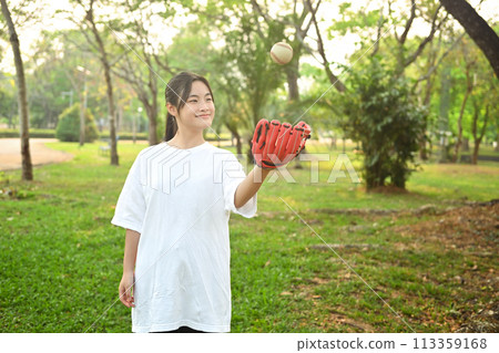 Smiling teenaged girl playing baseball in the park on a sunny spring day Smiling teenaged girl playing baseball in the park on a sunny spring day 113359168