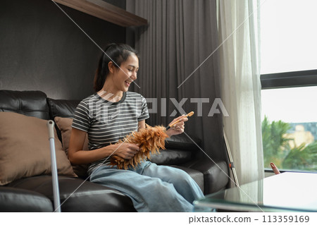Happy housewife enjoying domestic chores, cleaning up her house and singing 113359169