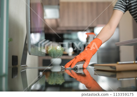 Close up housewife wearing rubber gloves cleaning table with microfiber 113359175