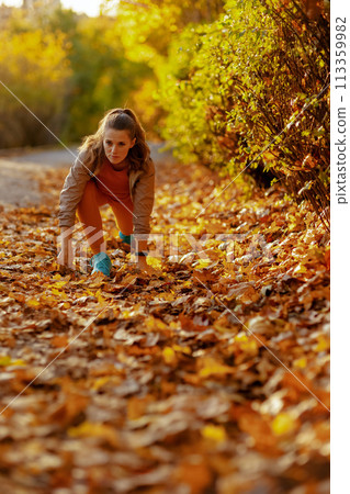 young woman in fitness clothes in park stretching young woman in fitness clothes in park stretching 113359982