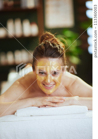 smiling modern woman in spa salon laying on massage table smiling modern woman in spa salon laying on massage table 113360003