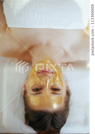 relaxed female in massage cabinet laying on massage table 113360009