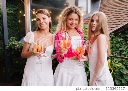 Portrait of happy females with with aprlol spritz celebrating hen party. Bride to be. White and pink style Portrait of happy females with with aprlol spritz celebrating hen party. Bride to be. White and pink style 113360217