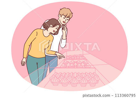 Young couple stands near showcase of pastry shop with cakes and desserts under transparent glass 113360795