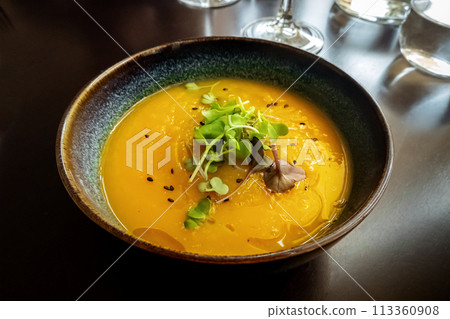 Microgreens on pumpkin soup at a vegan restaurant, elegant healthy dish 113360908