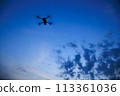 A drone flying in the sunset sky 113361036