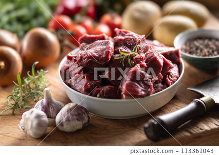 Pieces of chopped beef in a bowl with vegetables, ready for goulash 113361043