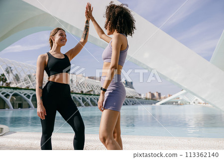 Happy female friends doing gesture of sport shake hand after exercising outside Happy female friends doing gesture of sport shake hand after exercising outside 113362140