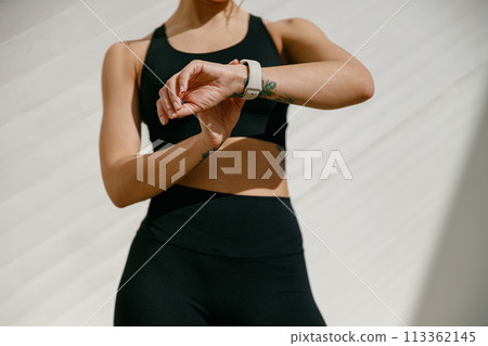 Close up of woman in sportswear looking on smartwatch after training. Outdoor sports in the morning Close up of woman in sportswear looking on smartwatch after training. Outdoor sports in the morning 113362145