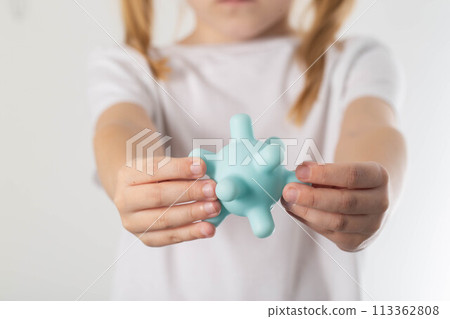 A blonde girl holds a model of a virus in her hands. Concept of ARVI and influenza virus in children, close-up 113362808