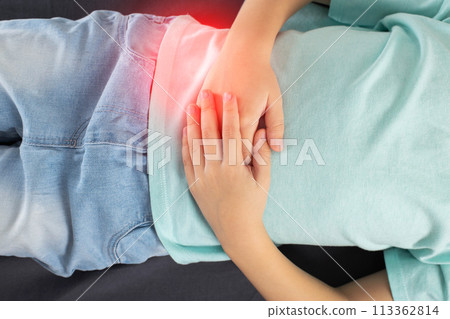 A little girl lies and holds her stomach, which hurts. Concept of diseases of the gallbladder and biliary tract. Concept of worms in children, close-up A little girl lies and holds her stomach, which hurts. Concept of diseases of the gallbladder and biliary tract. Concept of worms in children, close-up 113362814