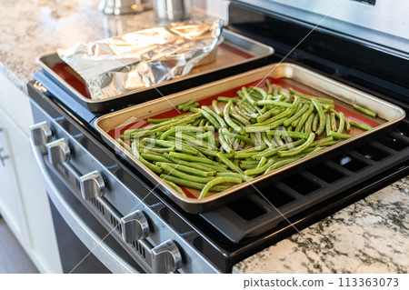 Watch as fresh green beans are beautifully roasted to perfection on a baking sheet with a silicone mat, adding a burst of flavor to your meal. 113363073