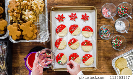 Flat lay. Creating snowflake-shaped cutout sugar cookies, dipped in chocolate, and adorned with different toppings. 113363157