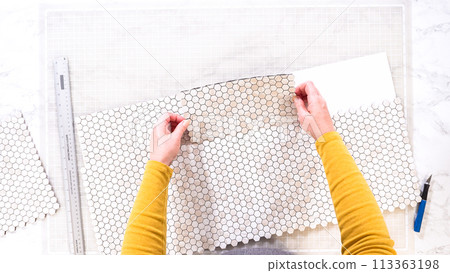 Flat lay. In the process of mounting peel and stick mosaic tiles onto a foam board, perfect for enhancing a food photography studio's aesthetic. 113363198